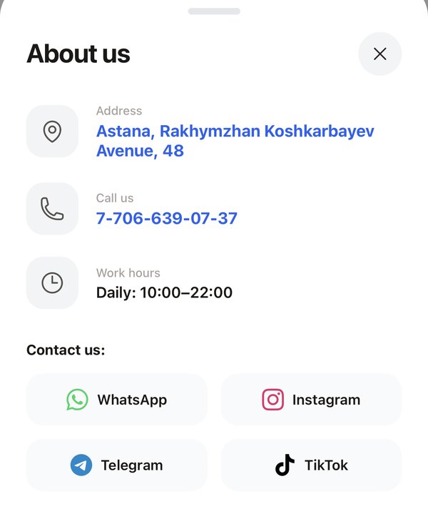 “About us” window of a flower shop storefront: address in Astana, phone, opening hours and social media